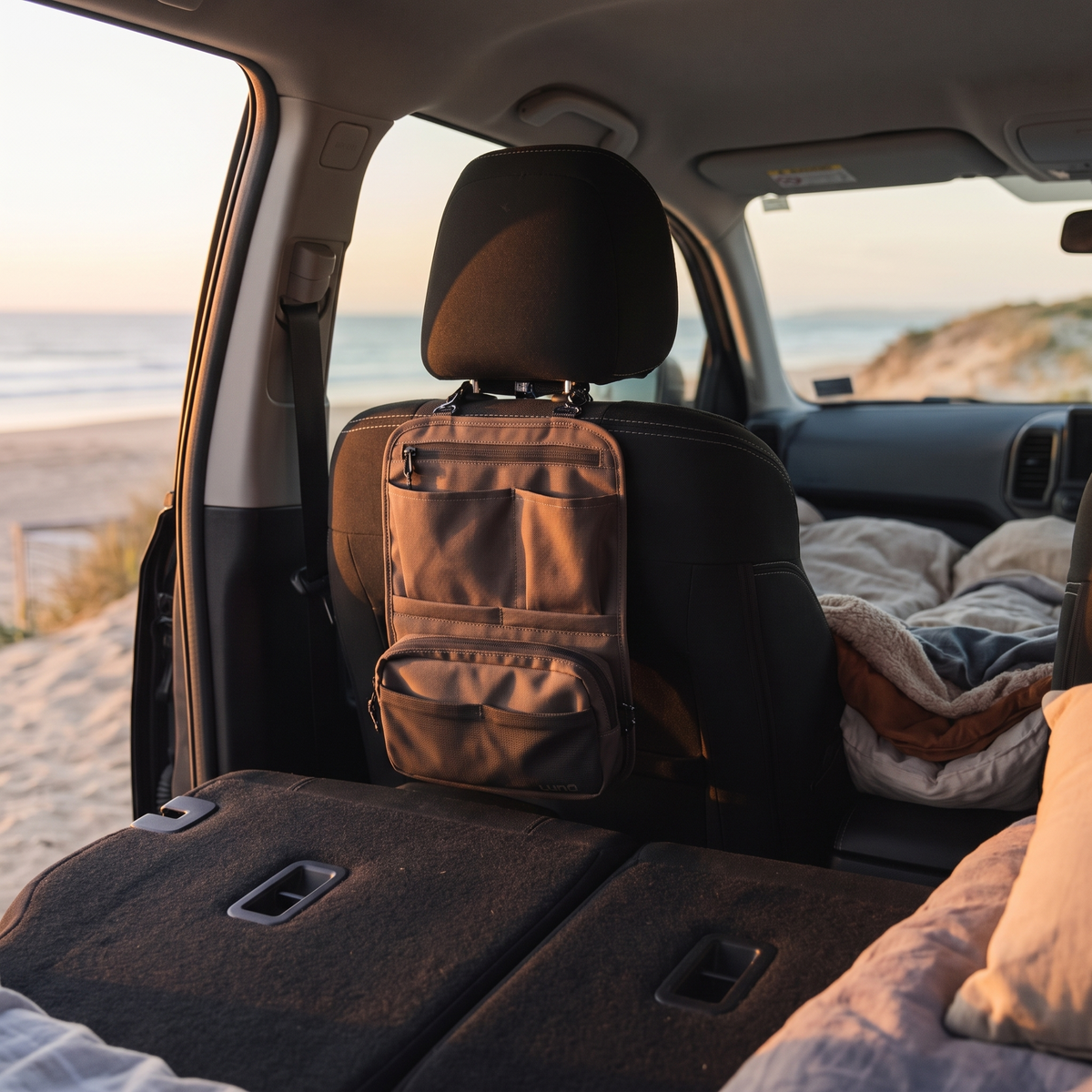 Headrest Organiser with Removable Pouch – in use at a coastal beach campground at sunset